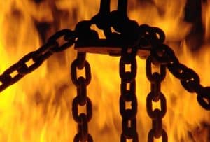 Schwarze Eisenketten vor lodernden Flammen als Sinnbild für den Weltenbaum des Bösen und den Dämonenkampf im schamanischen Seminar.